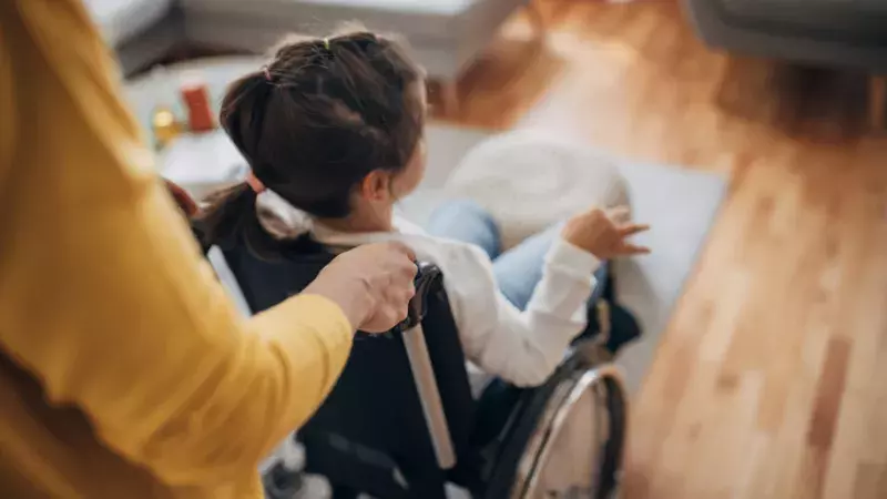 Mère poussant sa fillette assises dans un fauteuil roulant 